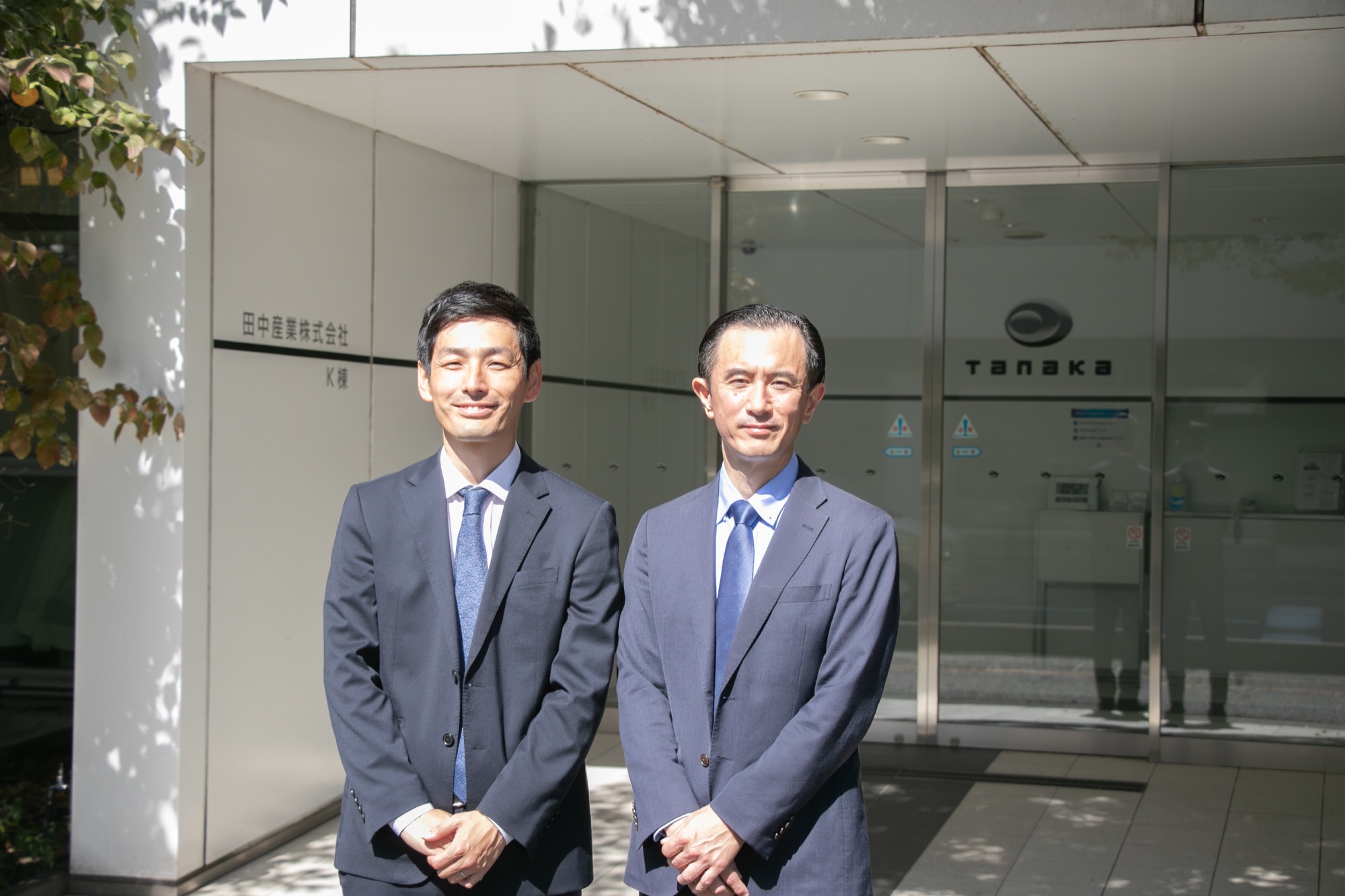田中産業株式会社のエントランス前に並ぶ志賀様と山口様