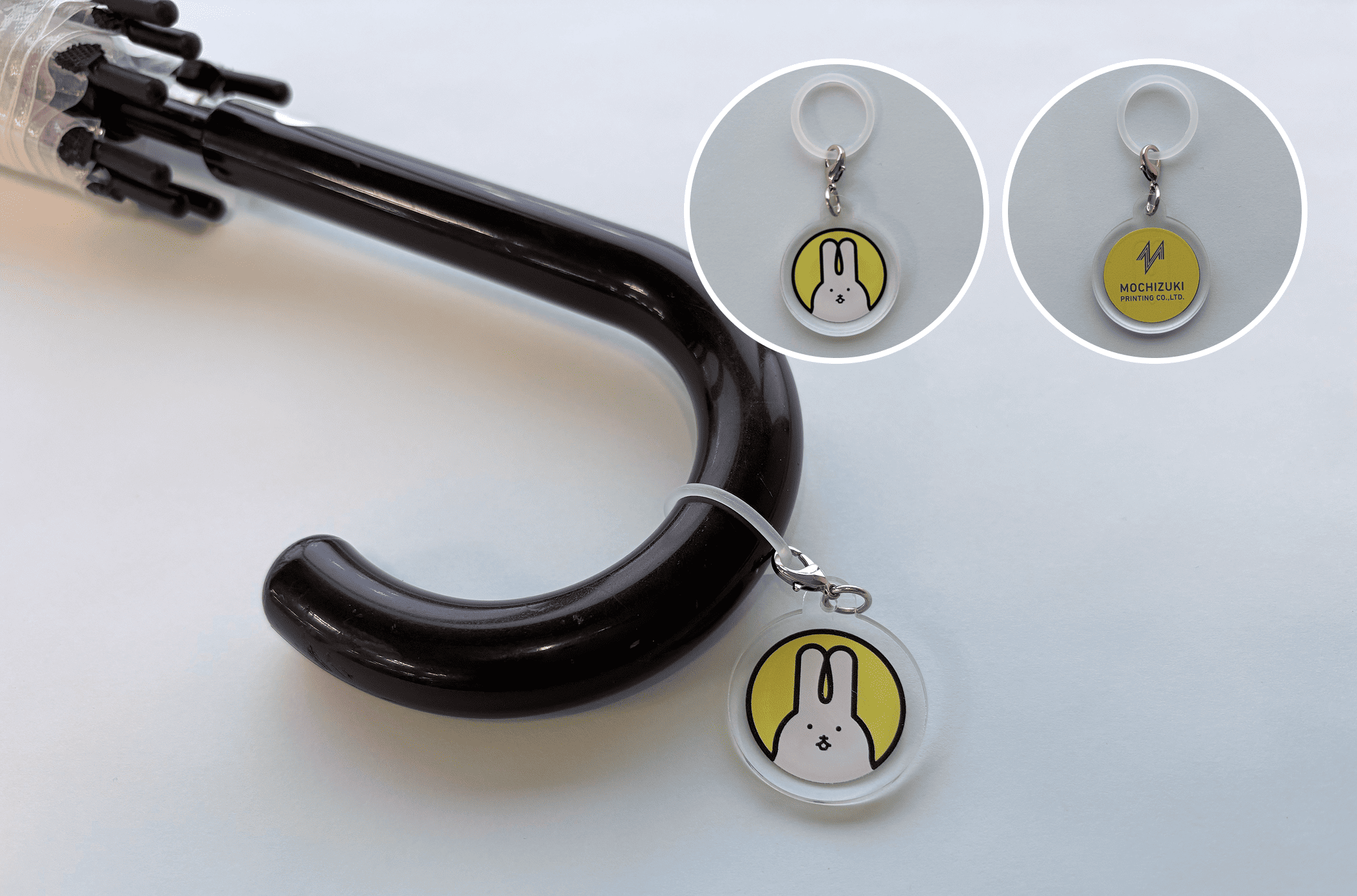 傘の持ち手に付けた、うさぎのキャラクター入りの丸いアクリルチャーム。キャラクター入りとロゴ入りのチャームも添えている